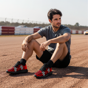 Man sitting on a dirt track wearing red and black checkered shoes