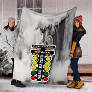 Two woman holding a large blanket with drag racing design outdoors.
