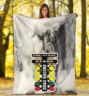 woman holding a large blanket with drag racing design in a forest setting