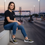 a woman sitting at a drag track wearing a drag racing tree logo sleep ons shoes