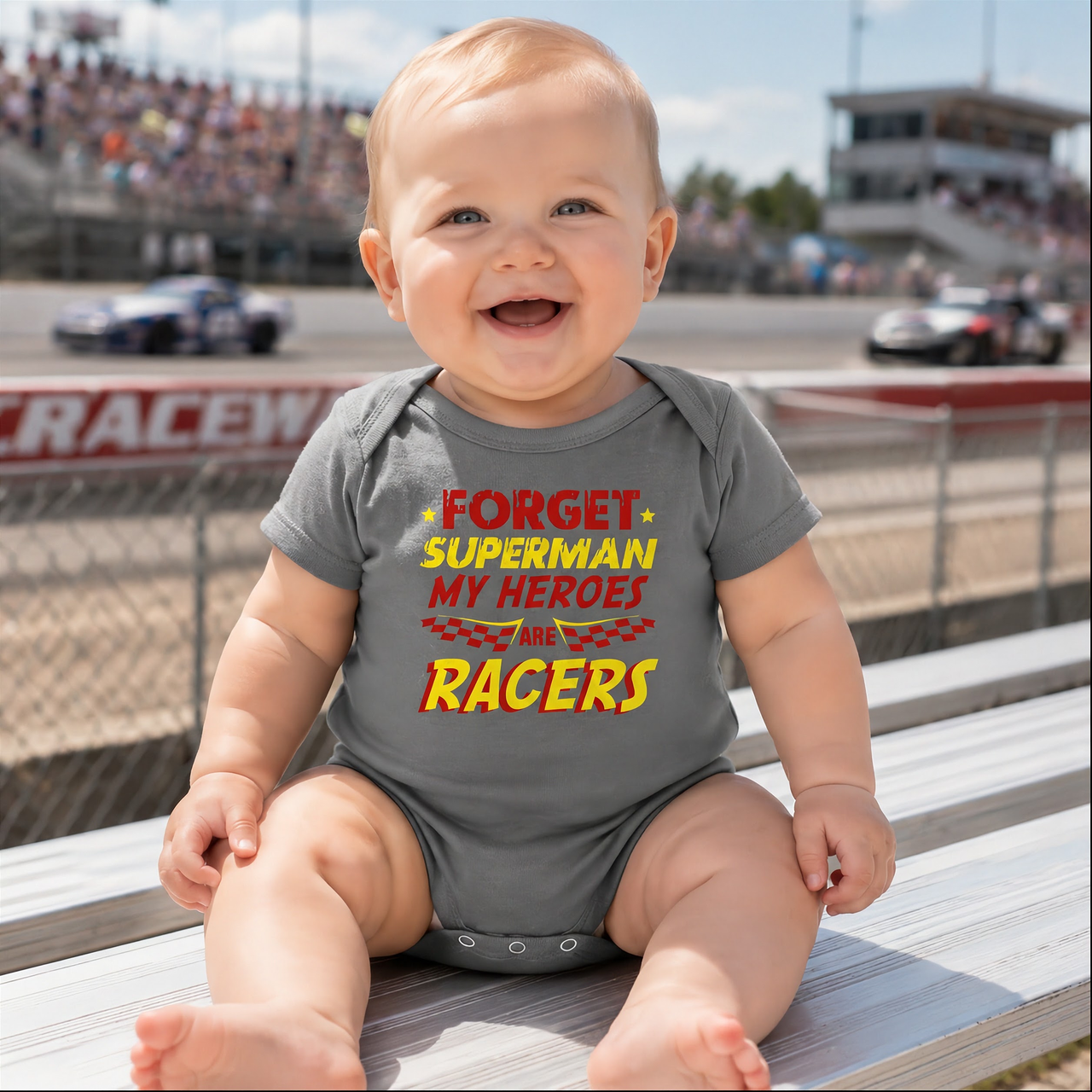 A youth t-shirt, cozy hoodie, and infant bodysuit displaying the fun text "Forget Superman My Superheroes Are Racers" in bold, comic-book style typography with checkered flag accents, set against a seamless white background.