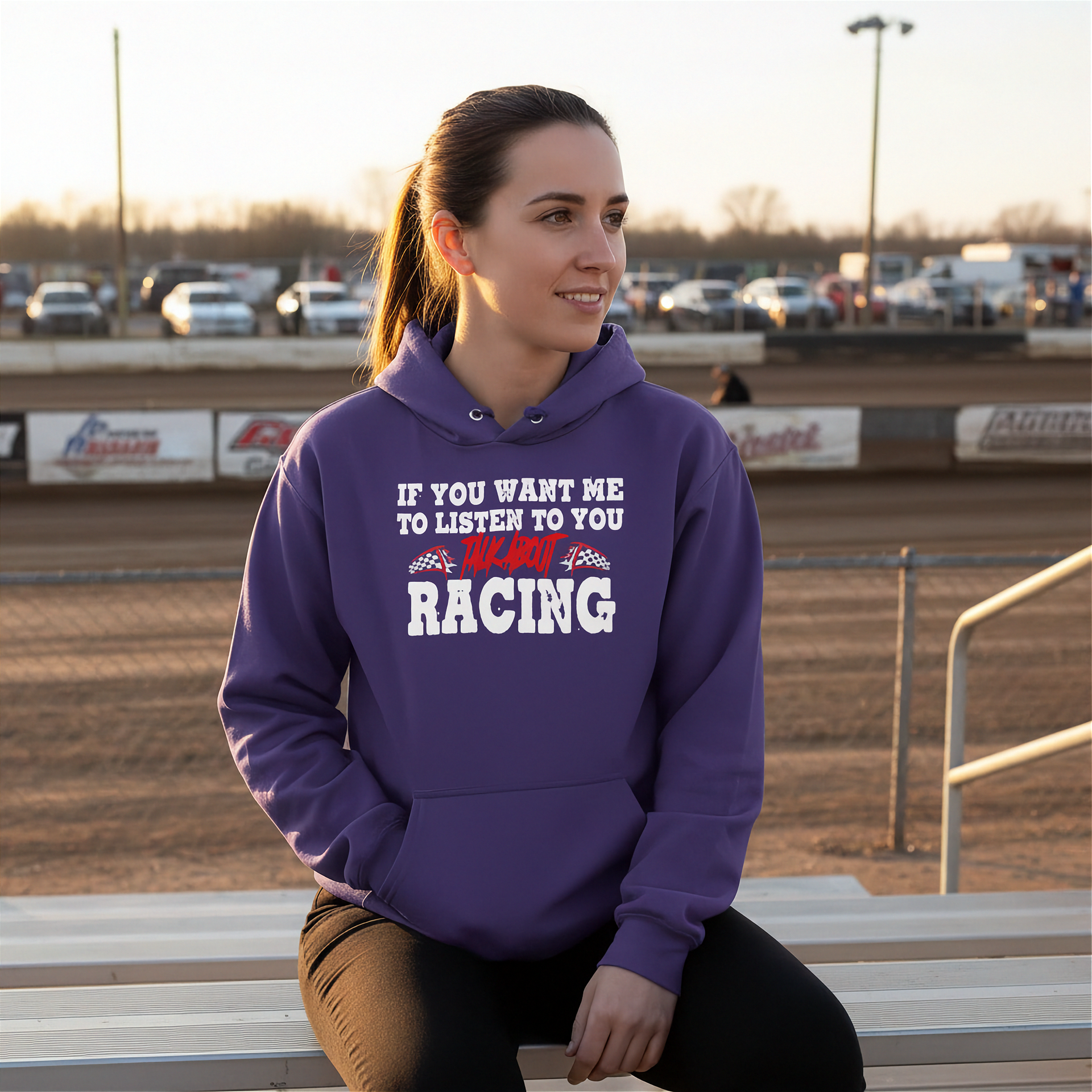 Woman wearing a purple hoodie with racing-themed text at a race track.