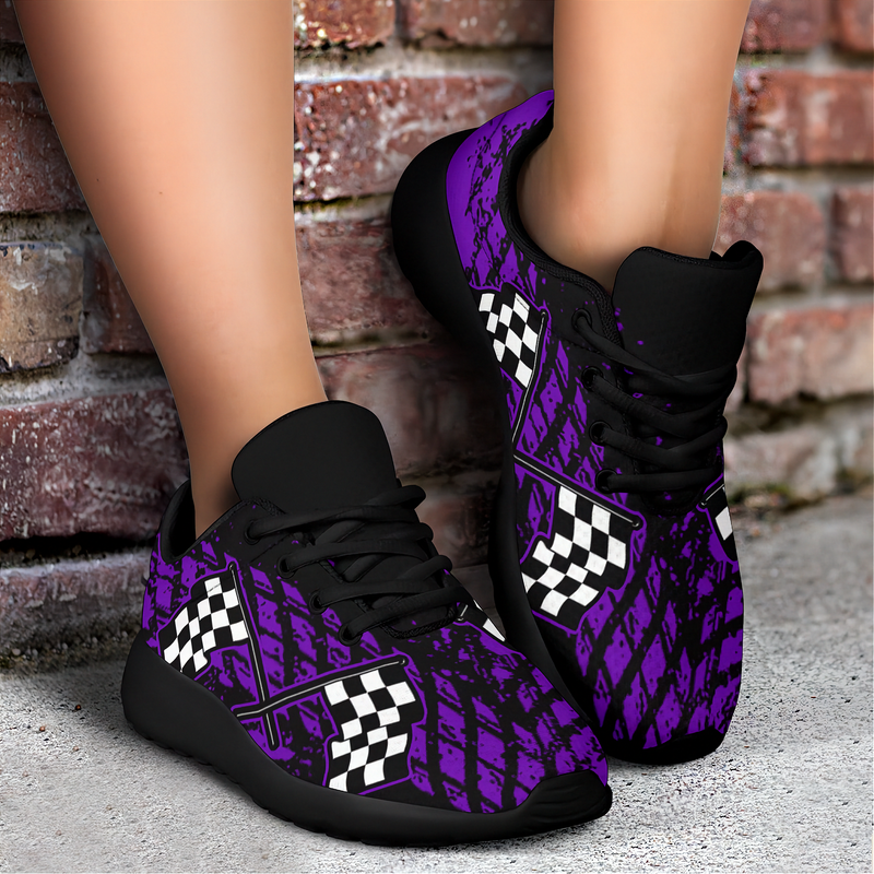 A pair of custom-designed dirt racing sneakers featuring a purple and black muddy tire track pattern with crossed checkered flags, shown from two different angles on a solid white background.