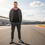 Man standing on a race track wearing a dark outfit with a scarf and wearing a checkered flag low top shoes