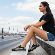 Woman sitting on a race track wearing black checkered shoes