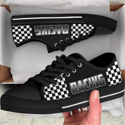 Black sneakers with 'Racing' and checkered patterns held by a hand, displayed against a white background.
