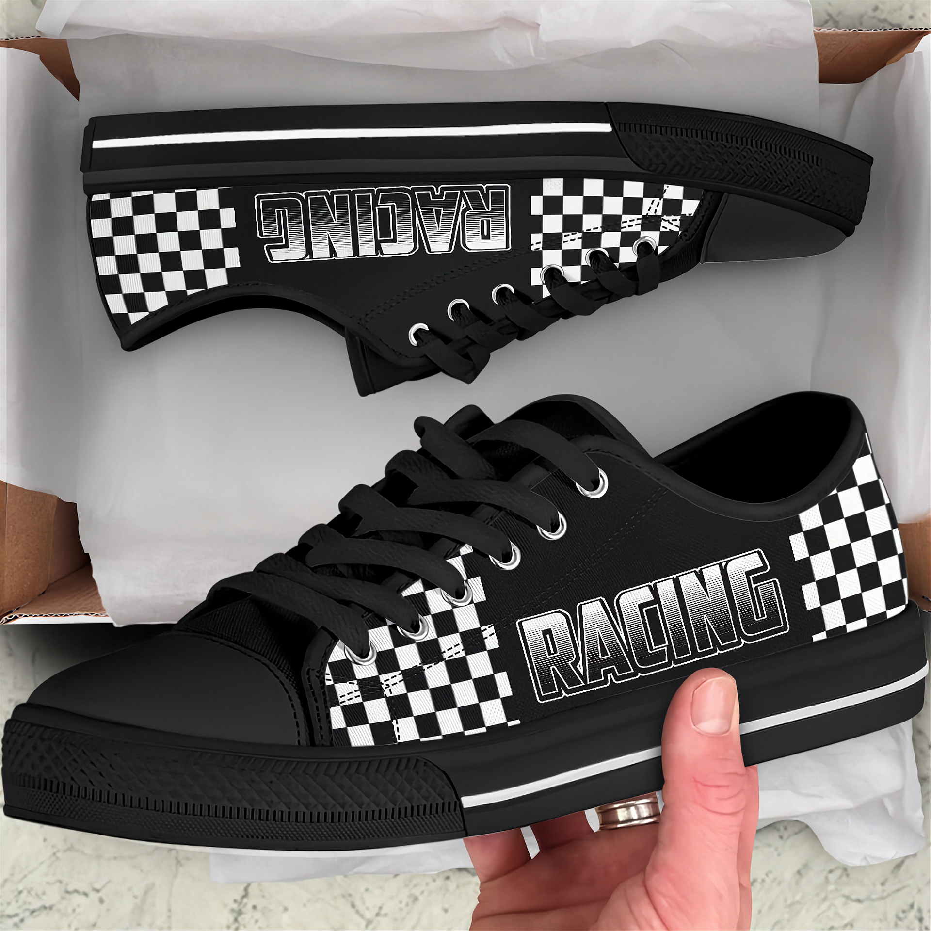 Black sneakers with 'Racing' and checkered patterns held by a hand, displayed against a white background.
