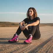 woman sitting in a a dirt track wearing a dirt racing pink and black boots