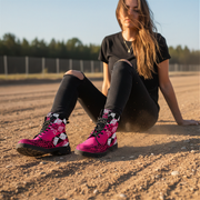 woman wearing pink and black  checkered patterned boots sitting on a dirt ground with trees in the background
