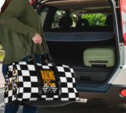 A stylish Racing Mom Travel Bag featuring a checkered flag pattern with the words "Racing Mom" and vibrant orange accents, carried by a model.