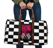 A stylish Racing Mom Travel Bag featuring a checkered flag pattern with the words "Racing Mom" and vibrant pink accents, carried by a model.