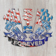 Close-up of the Racing Forever USA metal sign with piston artwork and red, white and blue flags against pale wood.