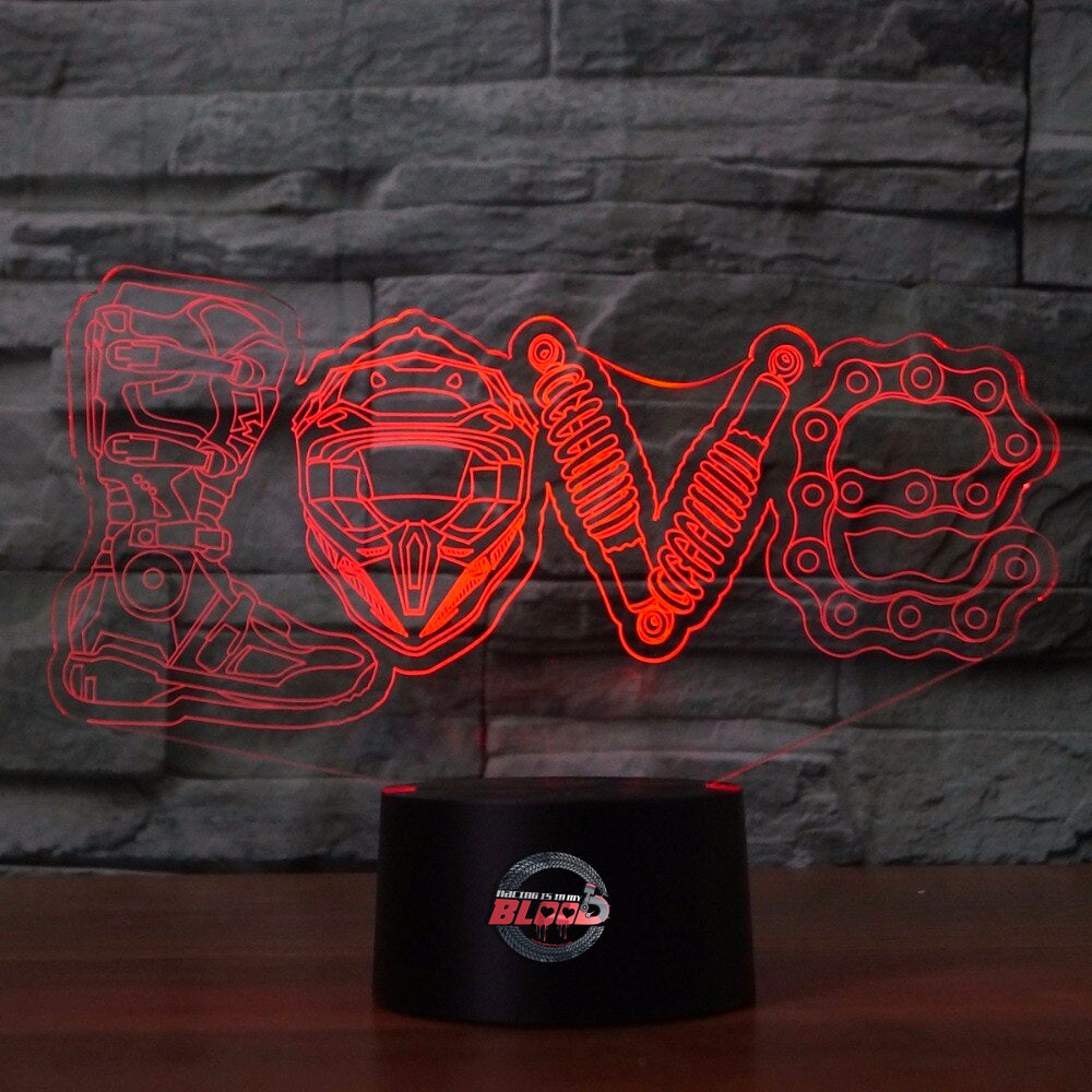 Love Motocross 3D LED Lamp showing a dirt bike rider jumping through a heart-shaped silhouette, glowing in a vibrant pink on a modern black base.