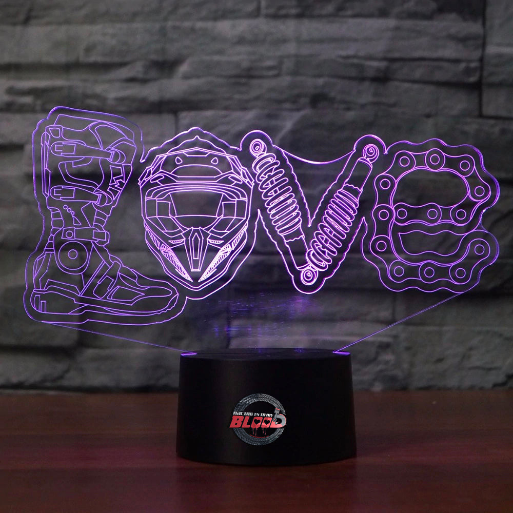 Love Motocross 3D LED Lamp showing a dirt bike rider jumping through a heart-shaped silhouette, glowing in a vibrant pink on a modern black base.