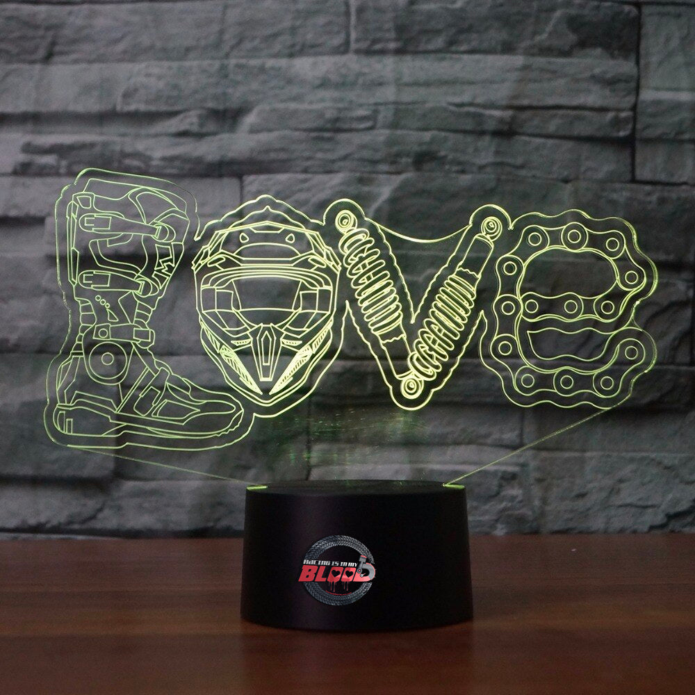 Love Motocross 3D LED Lamp showing a dirt bike rider jumping through a heart-shaped silhouette, glowing in a vibrant pink on a modern black base.