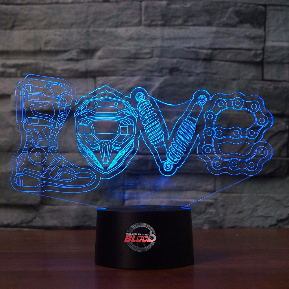 Love Motocross 3D LED Lamp showing a dirt bike rider jumping through a heart-shaped silhouette, glowing in a vibrant pink on a modern black base.