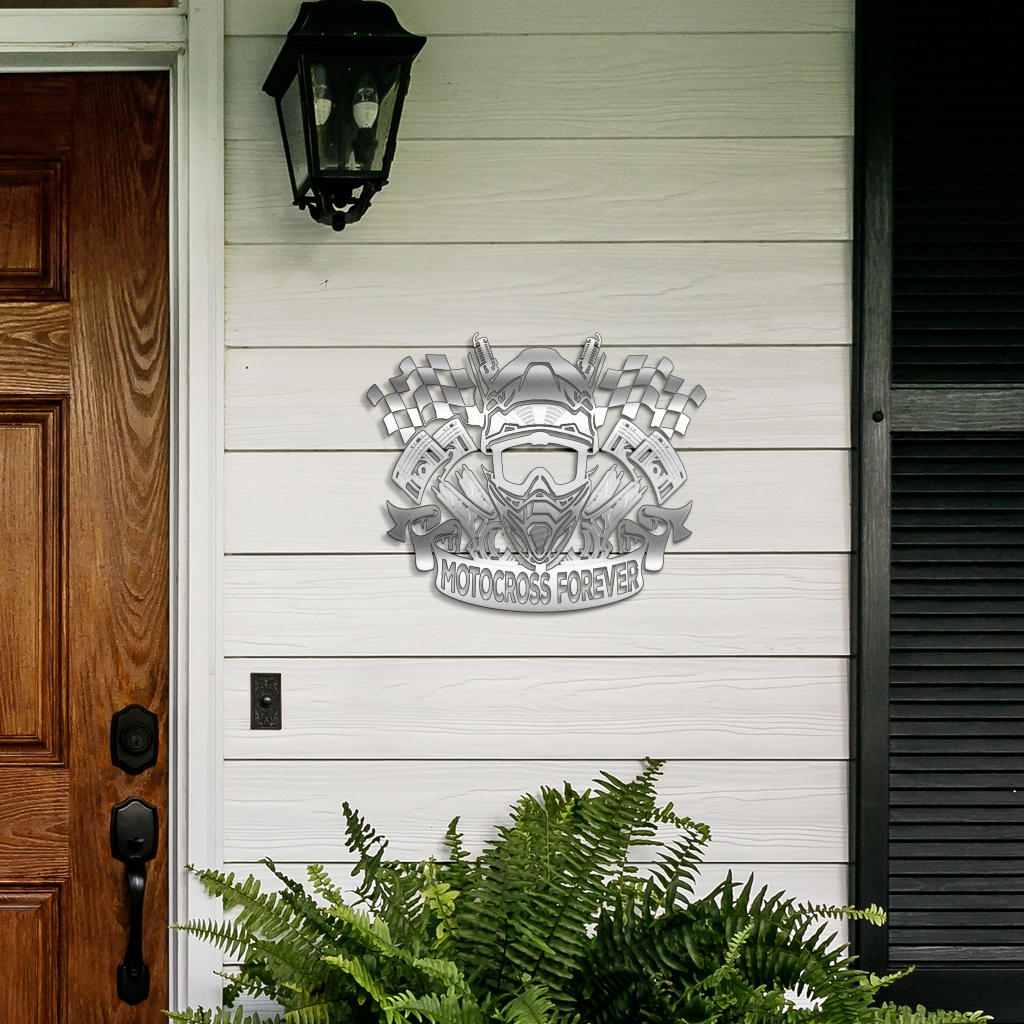Motocross Forever helmet sign on white porch siding beside a wooden door and fern.
