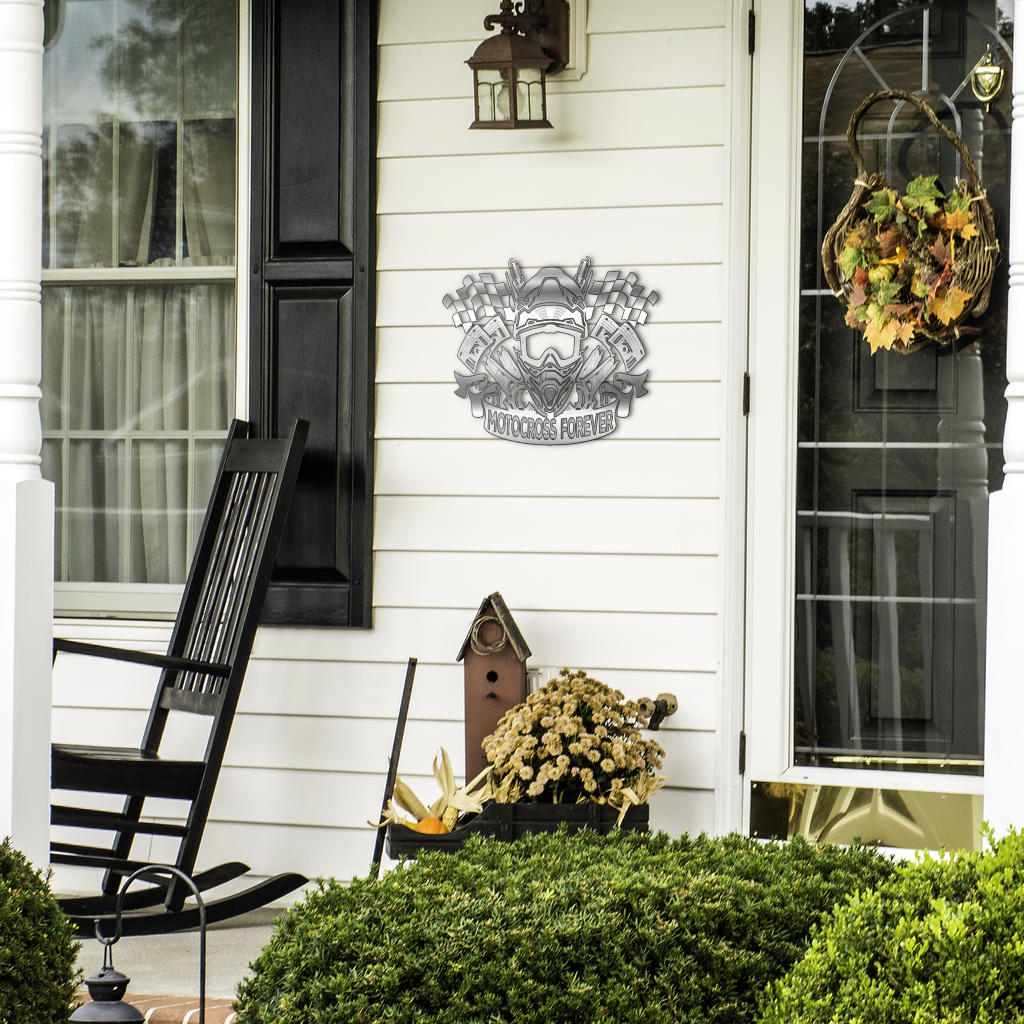 Motocross helmet and checkered flag sign beside a front door, black rocking chair and seasonal plants.