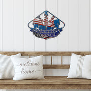 Patriotic dirt modified racing sign above a wooden bench with white cushions.