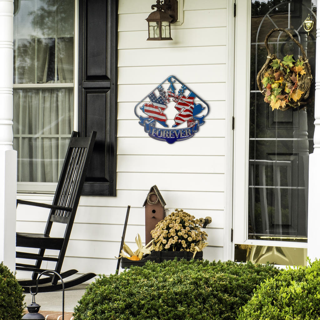 Patriotic sprint car metal sign beside a front door, black rocking chair and seasonal plants.