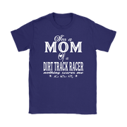 Premium black apparel mockup featuring a woman sitting on the wooden grandstand bleachers at a dirt track arena, wearing a soft custom t-shirt with a bold white graphic that reads "I'm a MOM of a DIRT TRACK RACER nothing scares me".