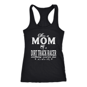 Premium black apparel mockup featuring a woman sitting on the wooden grandstand bleachers at a dirt track arena, wearing a soft custom t-shirt with a bold white graphic that reads "I'm a MOM of a DIRT TRACK RACER nothing scares me".