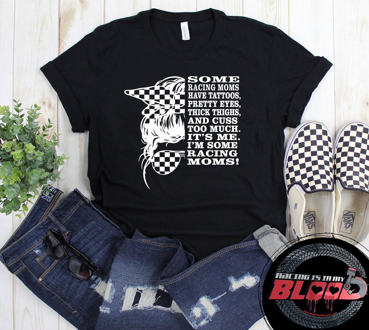 Premium black women's graphic t-shirt mockup featuring a checkerboard bandana messy bun graphic alongside bold white text that reads "SOME RACING MOMS HAVE TATTOOS, PRETTY EYES, THICK THIGHS, AND CUSS TOO MUCH. IT'S ME. I'M SOME RACING MOMS!".