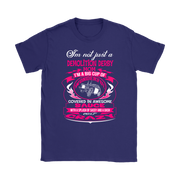 Premium women's black graphic t-shirt mockup featuring a vibrant pink and white custom design that reads "I'm not just a Demolition Derby Mom, I'm a big cup of wonderful covered in awesome sauce with a splash of sassy and a dash of crazy" with a derby car illustration.