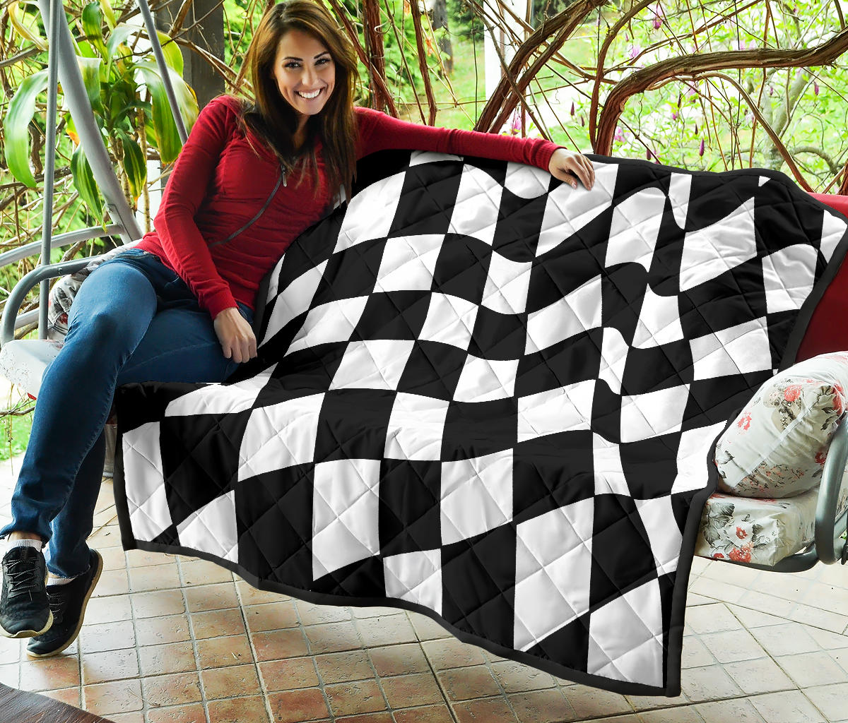 A woman sitting in her porch close to a black and white checkered quilted blanket.