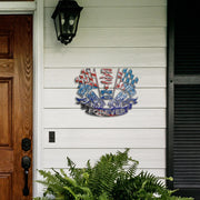 Racing Forever metal sign displayed on white porch siding beside a wooden front door and fern.