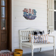 Racing Forever metal sign on white porch siding above a white bench with decorative pillows.