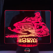 Snowmobile 3D LED Lamp featuring a detailed high-performance sled silhouette glowing in a vibrant ice blue on a premium black base.