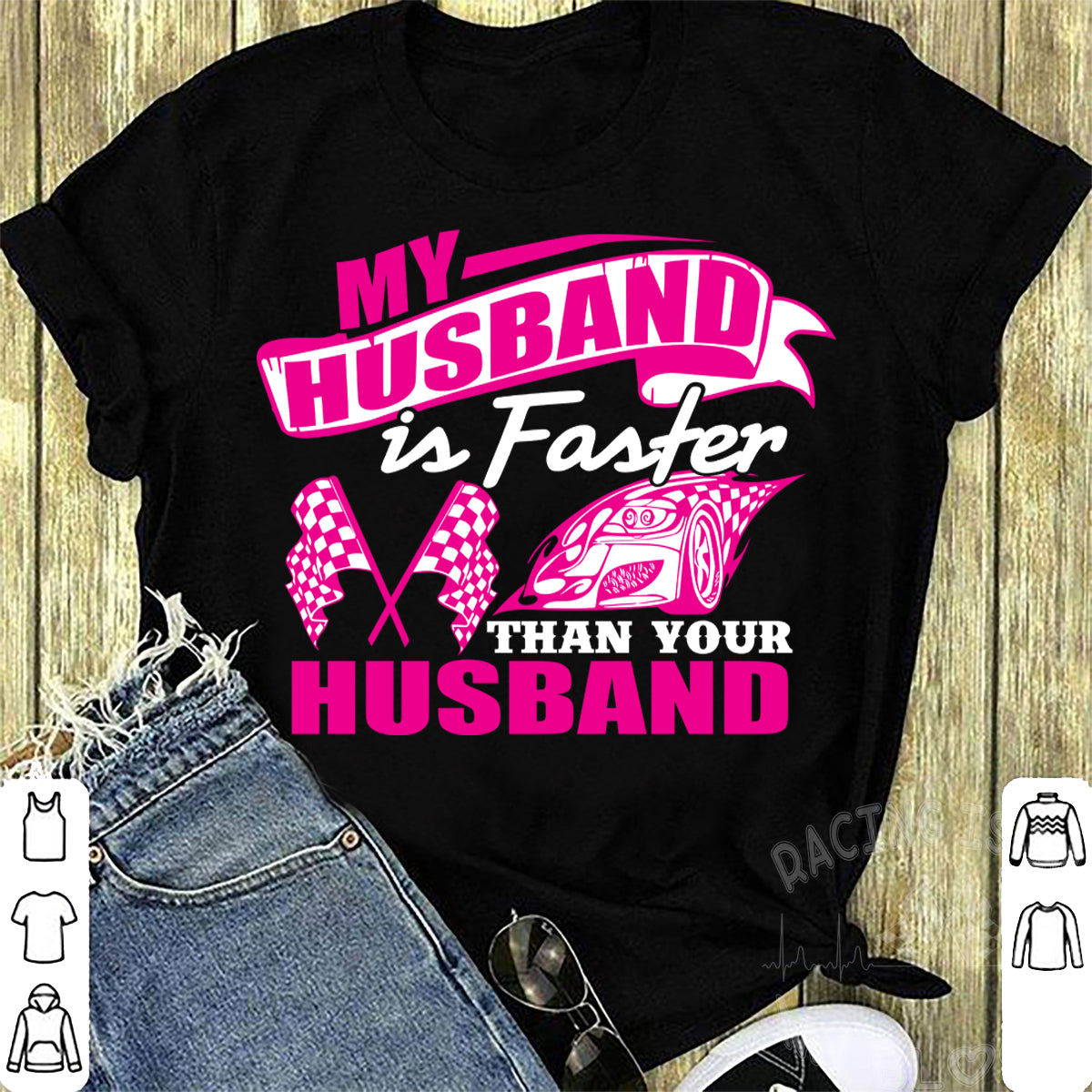 Woman sitting in the grandstands at a race track wearing a dark gray v-neck t-shirt with a pink and white graphic that reads "My Husband Is Faster Than Your Husband" alongside a race car and checkered flags.