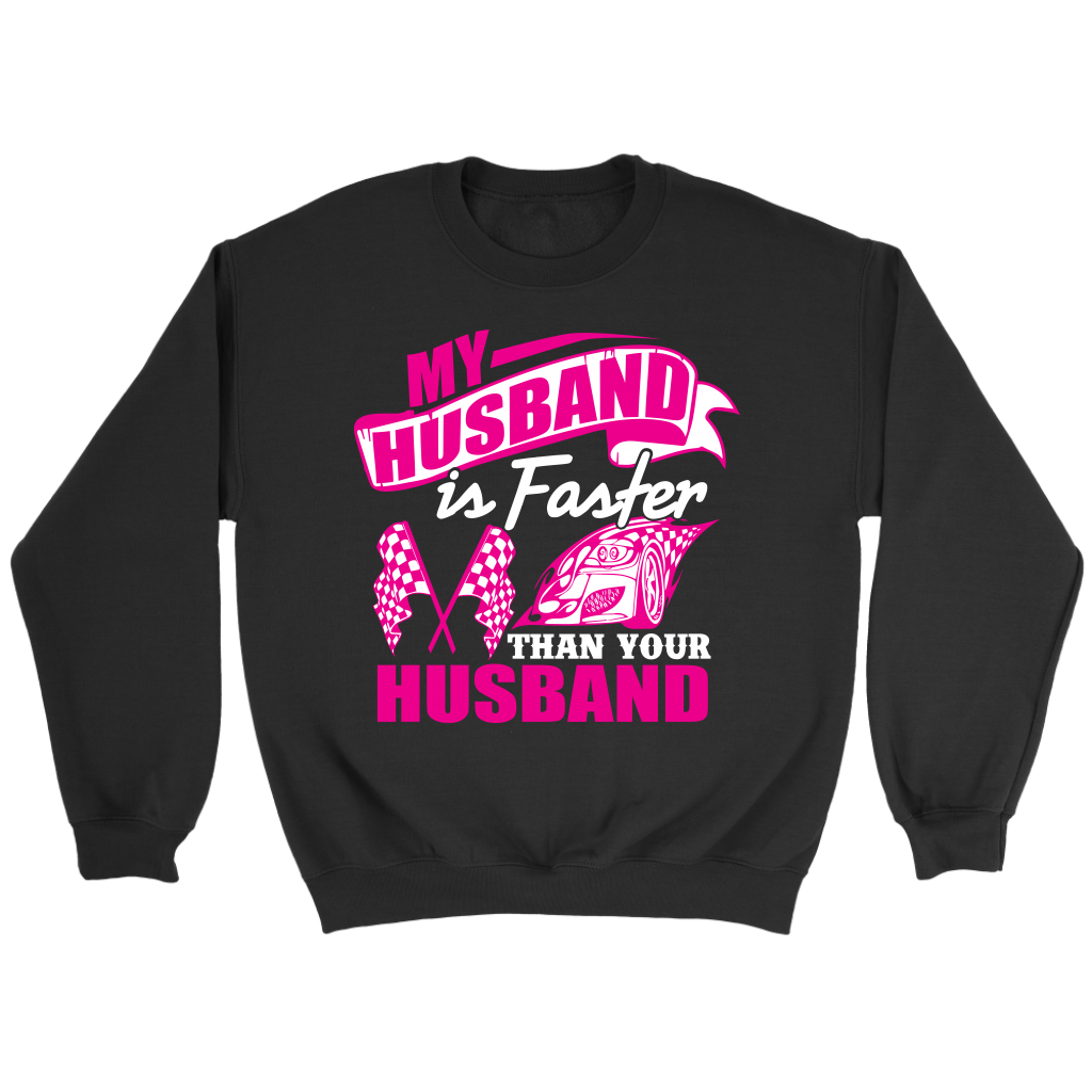 Woman sitting in the grandstands at a race track wearing a dark gray v-neck t-shirt with a pink and white graphic that reads "My Husband Is Faster Than Your Husband" alongside a race car and checkered flags.