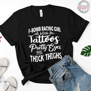 Women's F-Bomb Racing graphic apparel featuring the bold "Girl With Tattoos, Pretty Eyes, And Thick Thighs" slogan available in t-shirts, racerback tanks, and hoodies.