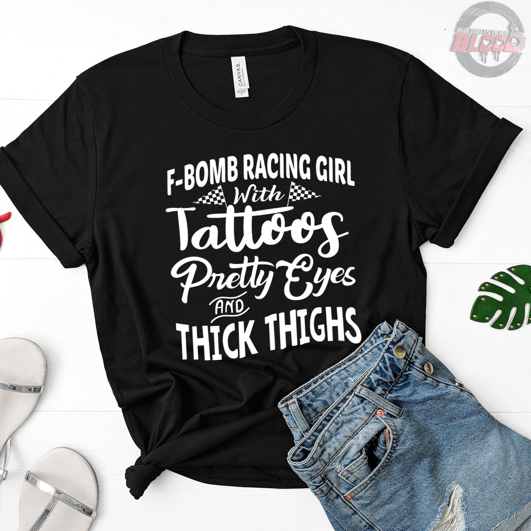 Women's F-Bomb Racing graphic apparel featuring the bold "Girl With Tattoos, Pretty Eyes, And Thick Thighs" slogan available in t-shirts, racerback tanks, and hoodies.