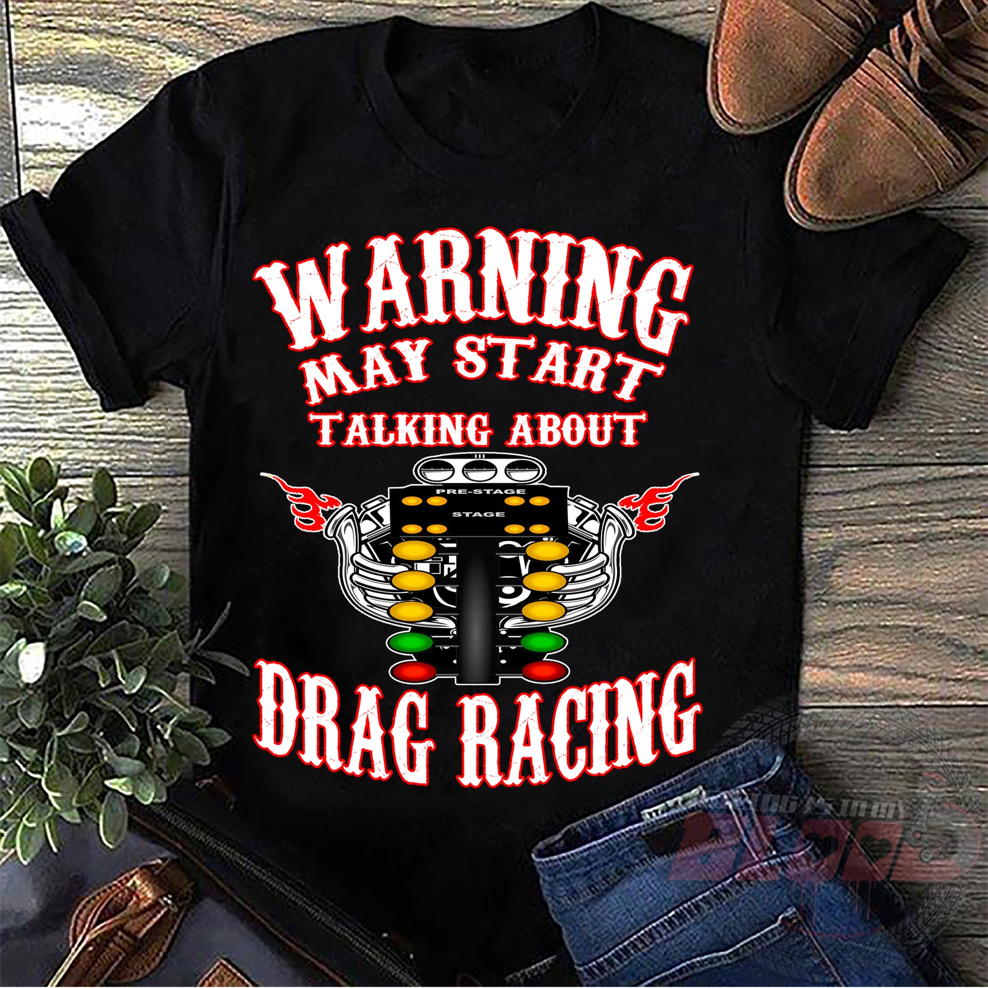 A premium black cotton t-shirt featuring the funny quote "Warning May Start Talking About Drag Racing" printed in bold white and high-visibility yellow typography, isolated flat on a solid white background.