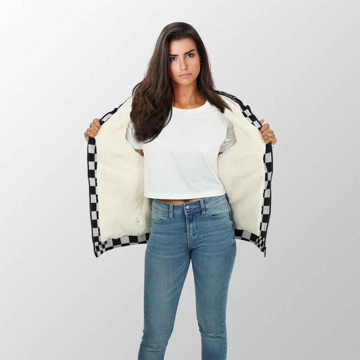 A stylish female race fan wearing the black "I'm Not Most Girls" sherpa jacket, with the hood up, standing under the bright LED lights of a racetrack grandstand, focusing on the textured lining and bold print.